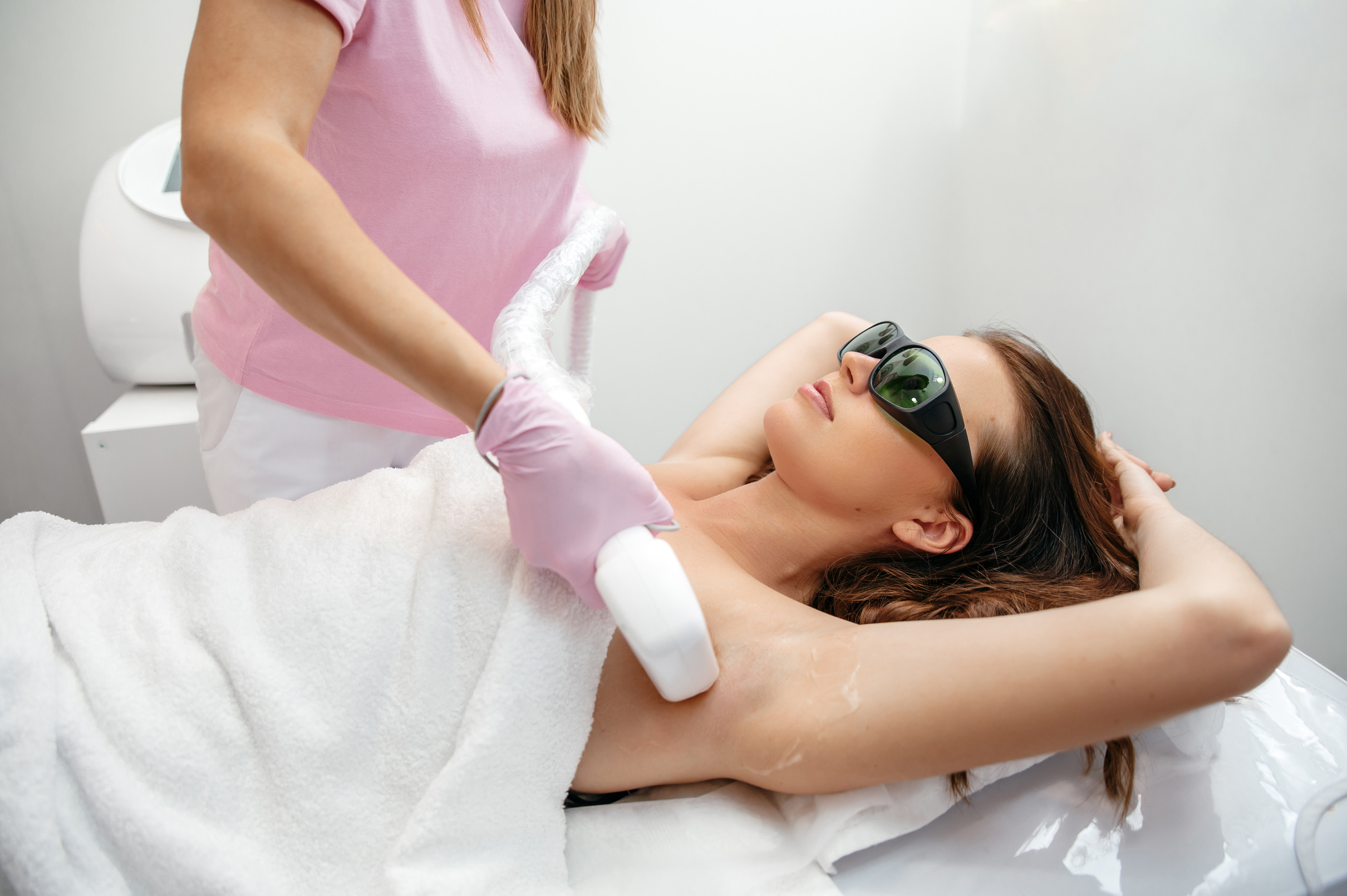 Hair removal by laser hair removal. Caucasian young woman lies on the couch with protective glasses during the procedure for removing unwanted hair with a laser machine